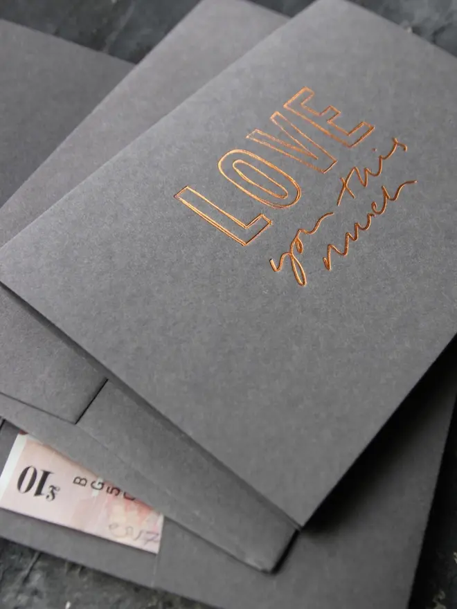 Hand foiled cash card or money wallet in a smoke grey colour in shiny bronze foil text which says ‘love you this much’.