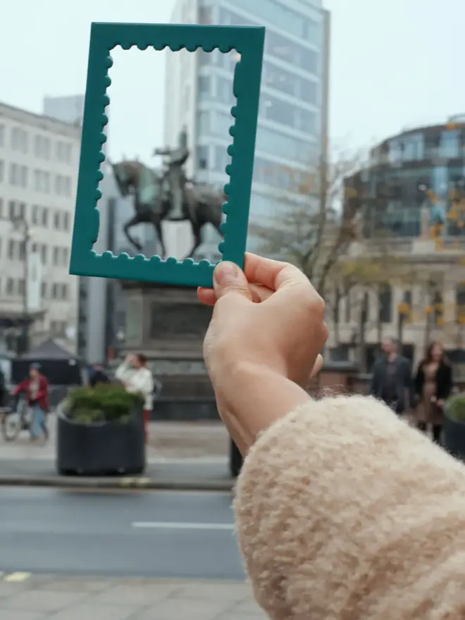 person holding empty teal stamp shaped frame mount