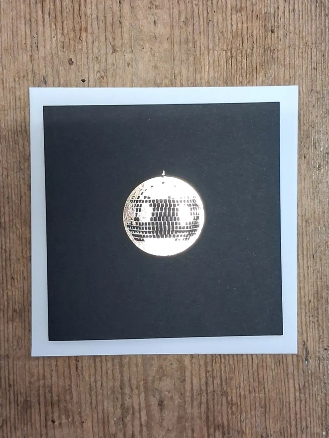 A greetings card printed in gold foil on black card with a picture of a disco ball