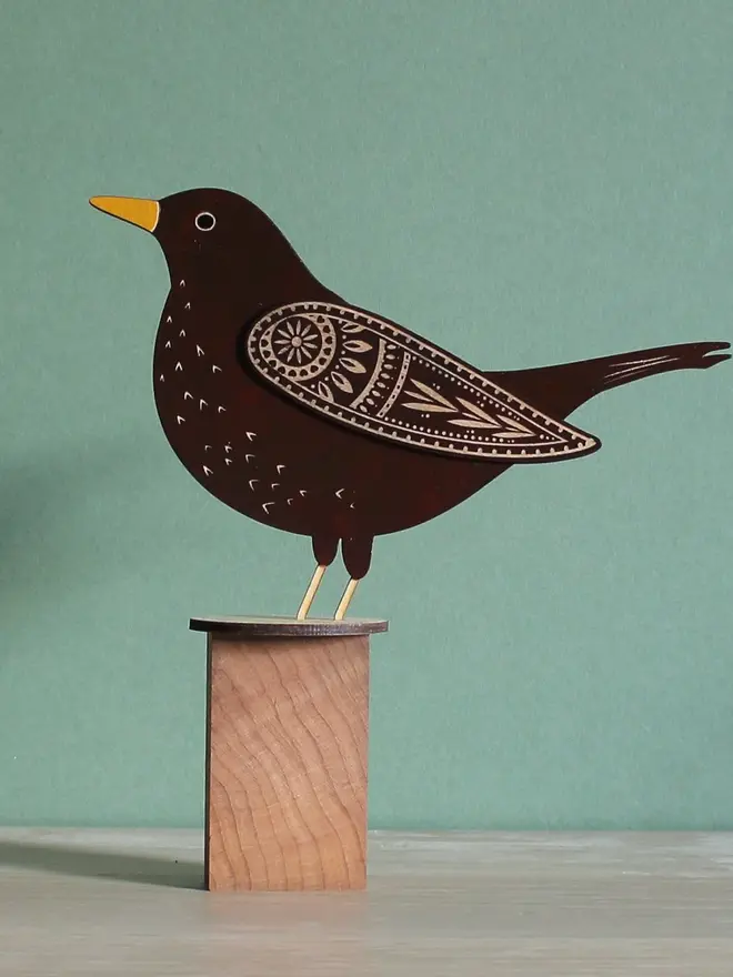 Standing Wooden Female Blackbird, black wooden bird standing on  a wooden platform. 