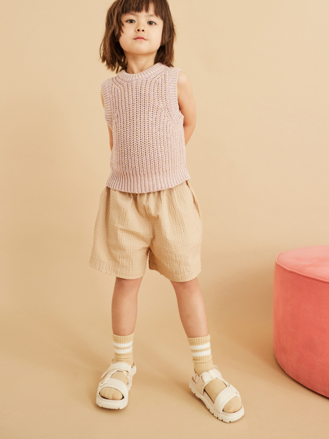 5 year old girl wearing knitted vest and oversize seersucker kids shorts looking very cool