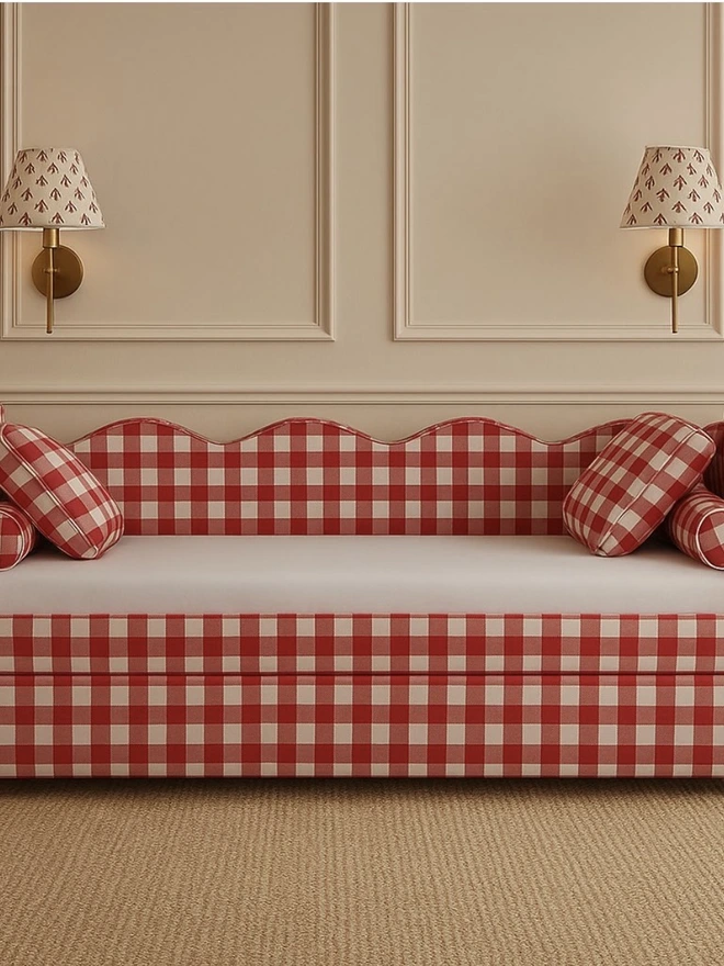 'the lochlan' red upholstered wavy children's trundle bed. a sofa-style children's bed with a wavy headboard in red gingham, with cushions and beddding.
