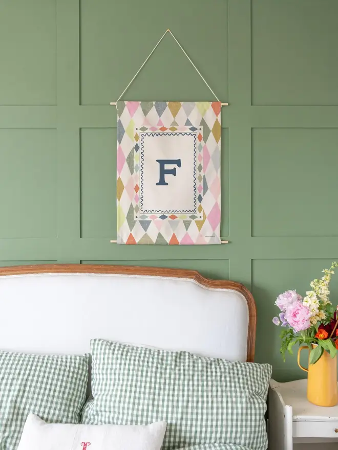 Harlequin Initial Fabric Banner, against a green wall. 