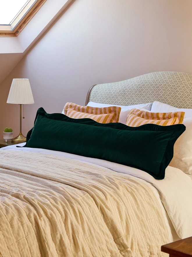 Handmade scalloped peacock velvet bolster cushion 130cm with feather pad paired with stripe linen cushions on bed, Kika Bespoke