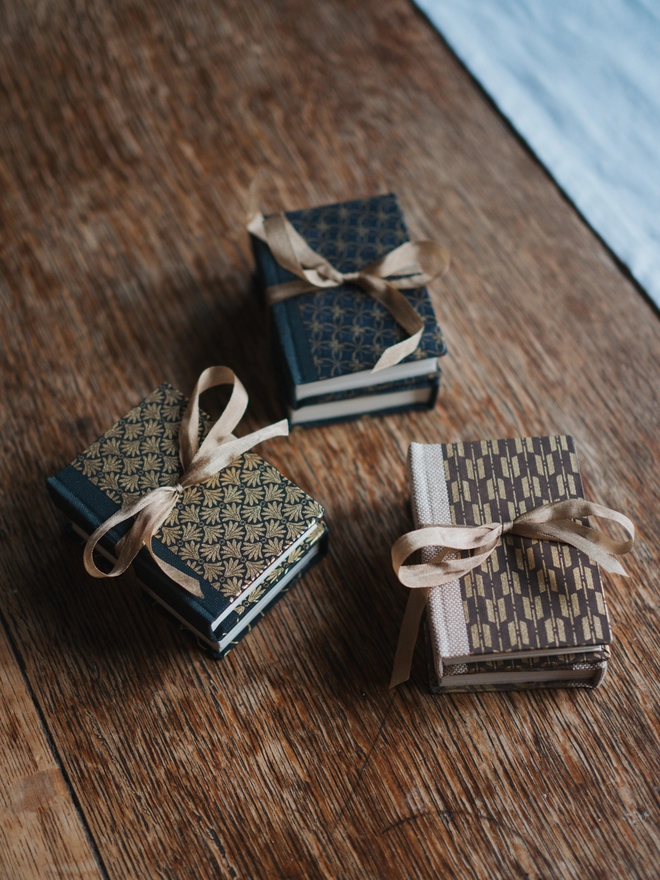 Three sets of miniature books in different patterned, each tied with a gold silk ribbon