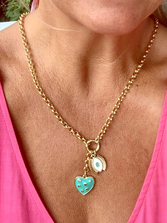 Woman wearing a pink dress and wearing a gold belcher chain necklace with two turquoise talisman charms hanging from it