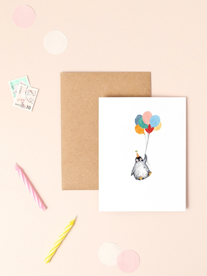 A cheerful illustration of a penguin holding a bunch of colorful balloons, exuding a sense of joy and celebration. The penguin's expressive eyes and the vibrant hues of the balloons create a playful and festive atmosphere. The design is minimalist yet heartwarming, making it a perfect choice for birthdays, congratulations, or any occasion that calls for a touch of whimsy.
