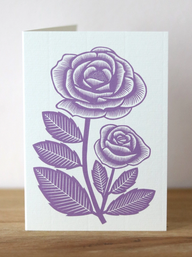 A greetings card featuring a purple rose flower based on an original linocut print