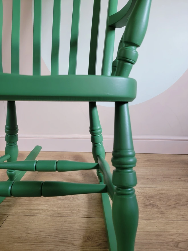 Close up of the legs of a wooden rocking chair painted green