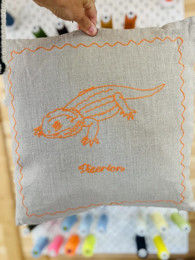 linen pillow with embroidered bearded dragon orange thread