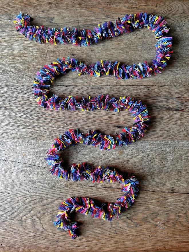 Two metre length of Rainbow Strinsel string tinsel on an oak table top