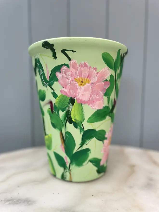 Unique hand-painted terracotta pot featuring pink peonies on a pale green background