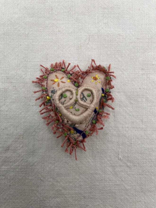 pink fringe brooch without label