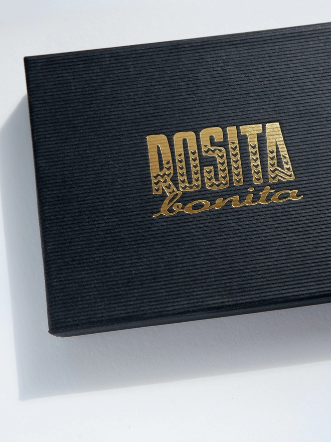 black ribbed paper box with Rosita Bonita Brand logo printed in gold