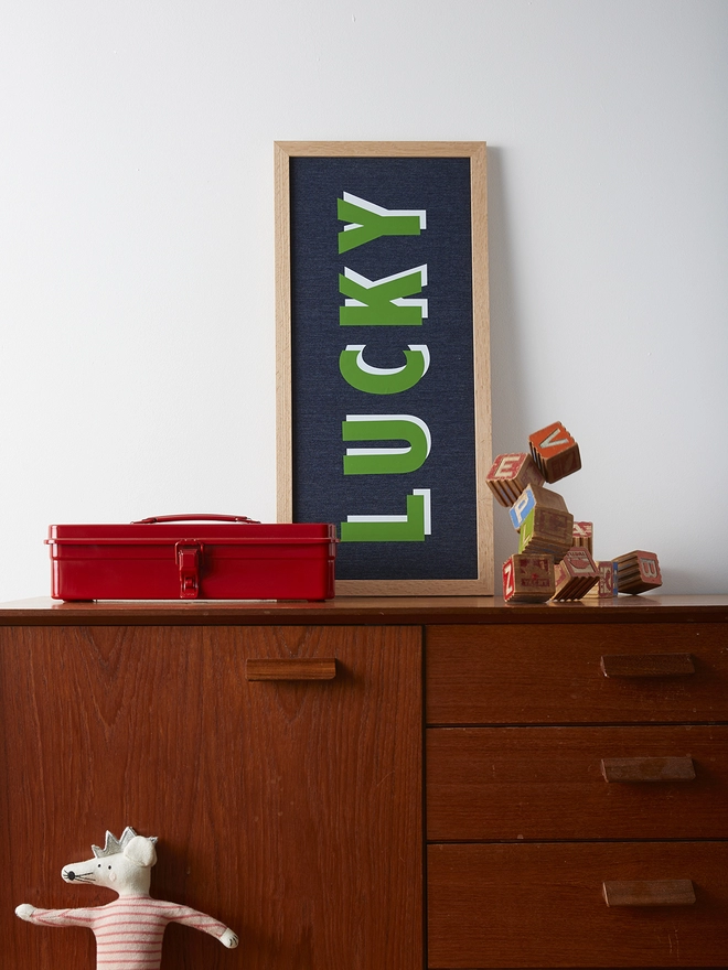Personalised framed green word with white highlights on denim fabric