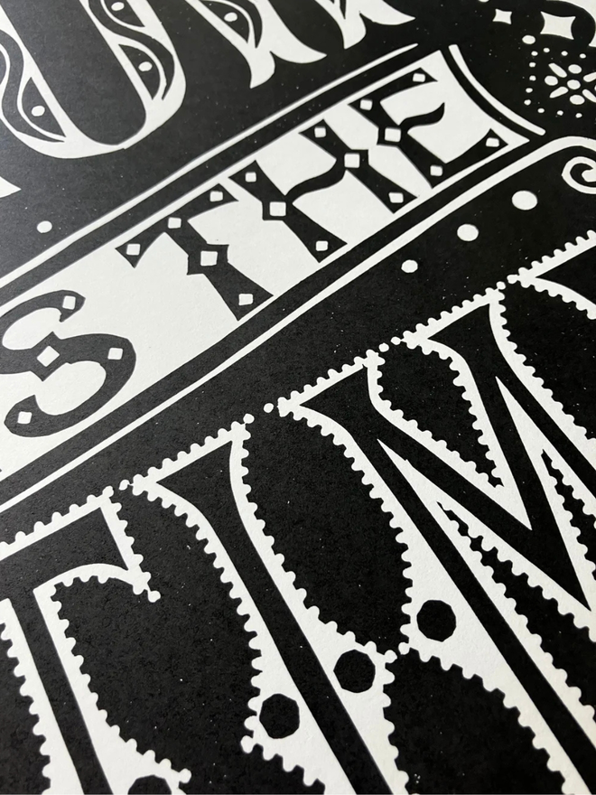 now is the time linocut. a linocut phrase printed on black paint.