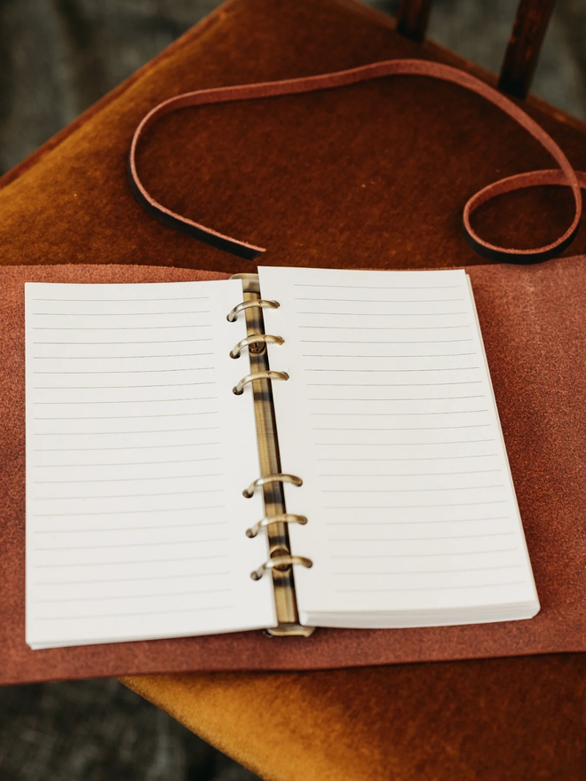 leather refillable ring binder. an open leather ring binder showing paper and ring mechanism inside.