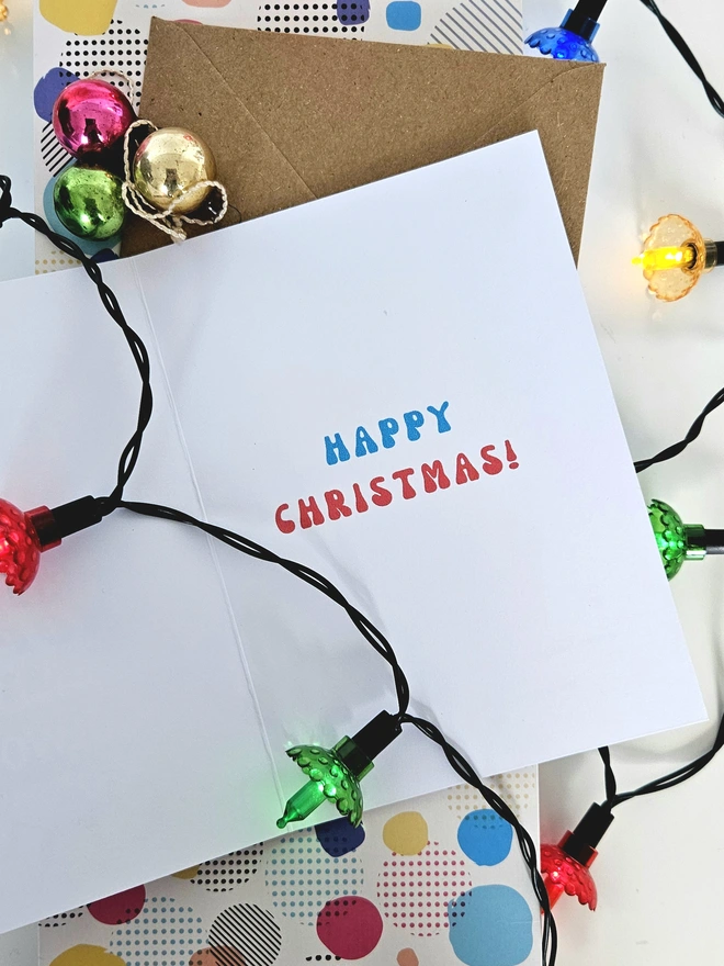 A photograph of the inside of a white card with colourful and retro style text that says happy Christmas.