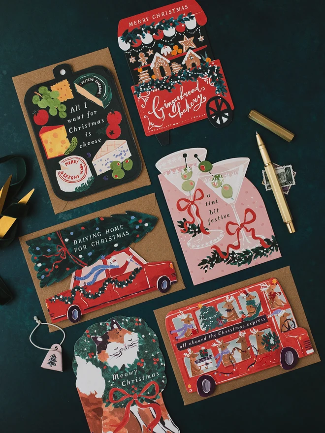 Gingerbread Cart Christmas card on a dark teal background with the Cheeseboard, Tini Bit Festive, Driving Home For Christmas and reindeer bus cards