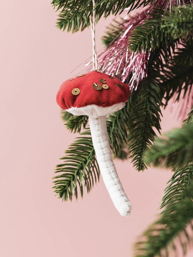 A velvet and sequin toadstool ornament on a tree