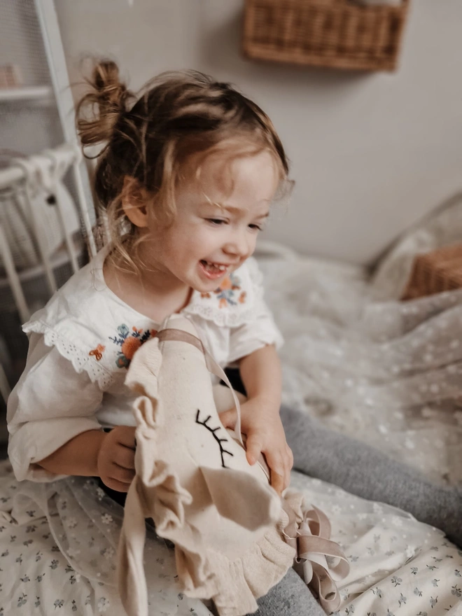 Horse Baby Rattle Toy, a child with a horse baby rattle toy in a bedroom surrounded by other bedroom accessories. 