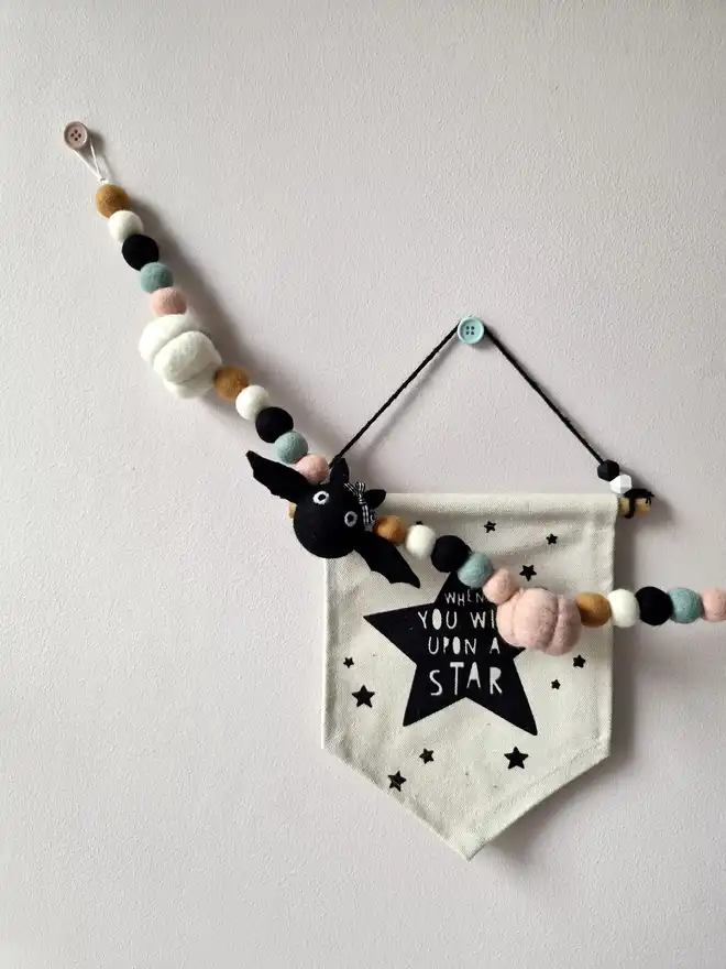 A neutral felt Halloween garland hung on a wall.
