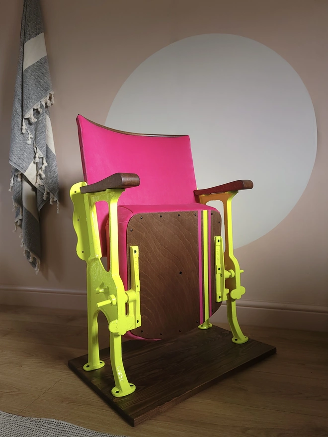 Hot pink vintage cinema seat with neon yellow legs and stripe design