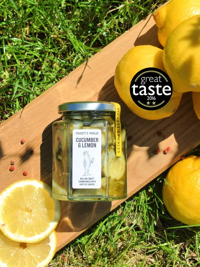 cucumber and lemon pickle. a jar of pickled cucumbers photographed on a wooden board with lemons.