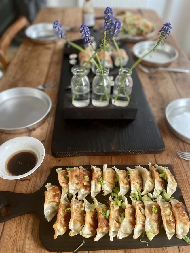 Long Charred Black Serving Board With Food and Flowers