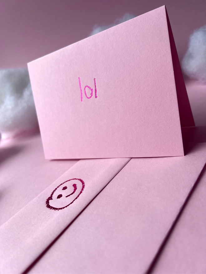 pastel pink coloured card with lol short for 'laugh out loud' or 'lots of love' hand foiled in kids hand writing