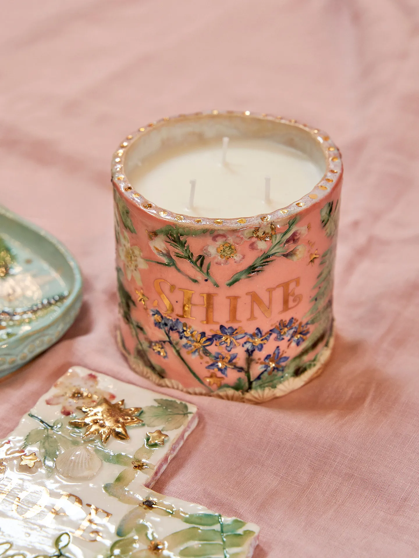 pink ceramic candle pot with floral decor and gold 'shine' text