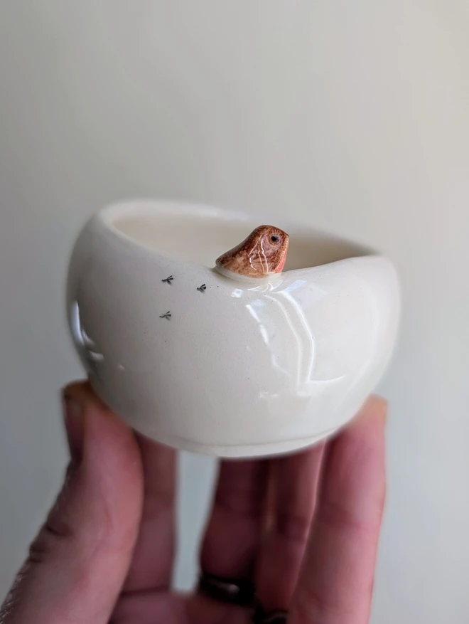 ceramic robin tealight candle holder with a tiny pottery robin on the edge and bird prints held in a hand