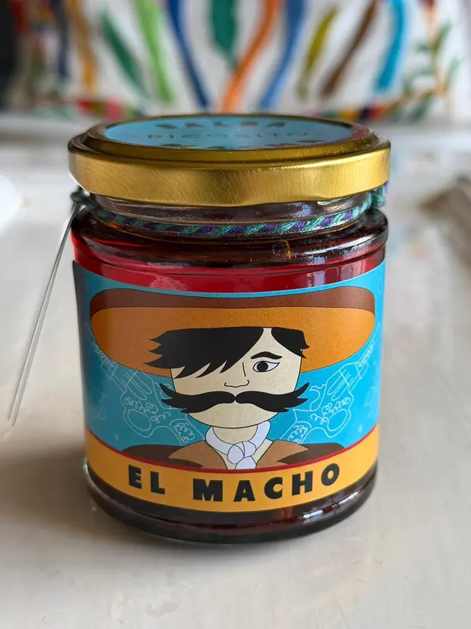 'El Macho' Salsa Jar (Set Of 1-4 Jars), a jar of salsa sitting on a kitchen counter top. It has the icon of a man on it. 