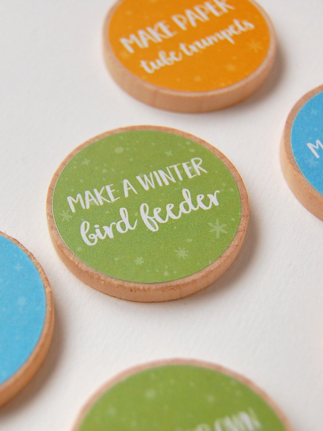 Several wooden tokens with brightly coloured labels lay on a white surface.