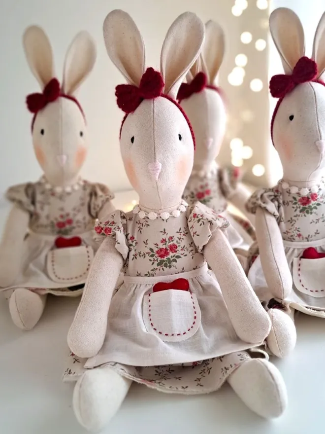 Group of handmade Veronica Bunny heirloom dolls dressed in matching floral outfits with linen aprons and red heart details