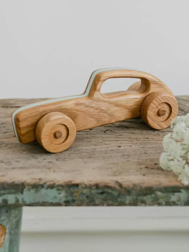 wooden toy racing car side view of the toy on a wooden bench