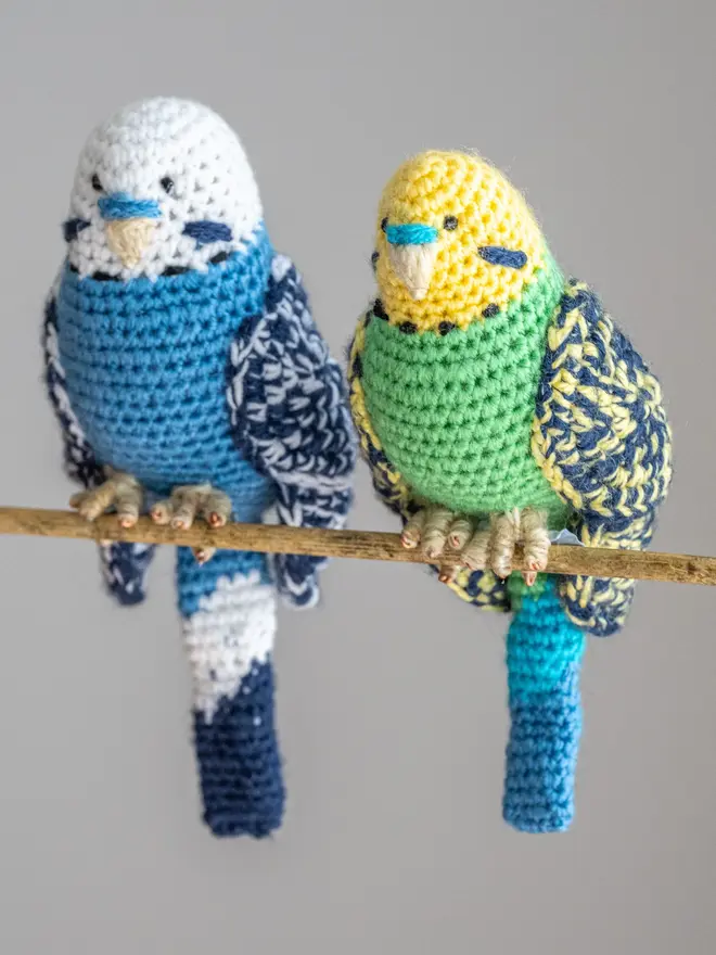 Budgerigar Hand Crocheted Figure, a blue and green crocheted bird sitting on a wooden poll. 