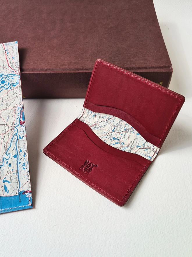 a red vegetable tanned leather wallet lined with a silk map from the Cold War by Natthakur