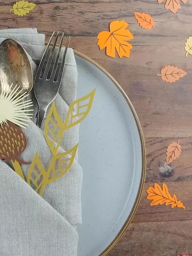 Autumn Leaf Confetti table setting suggestion. A plate with napkin, cutlery and paper decorations. 