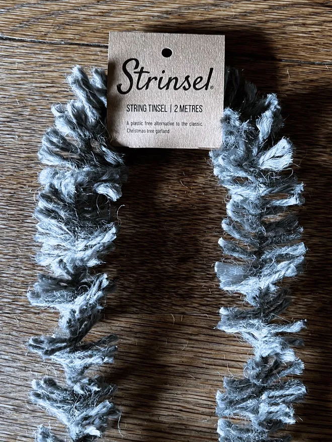 Silvery Pewter Strinsel - string eco tinsel packaged with kraft header label close up on oak table top