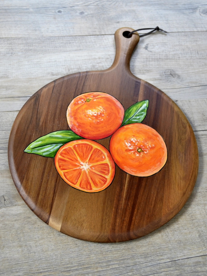 Wooden serving board with a handpainted design of some clementines