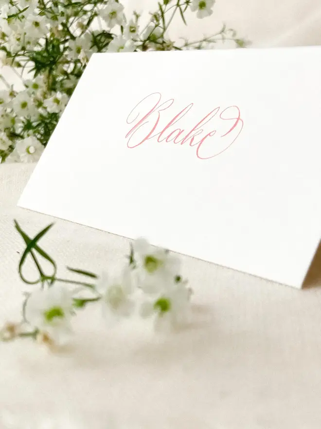 personalised calligraphy place cards. white place card with name in calligraphy pink ink.