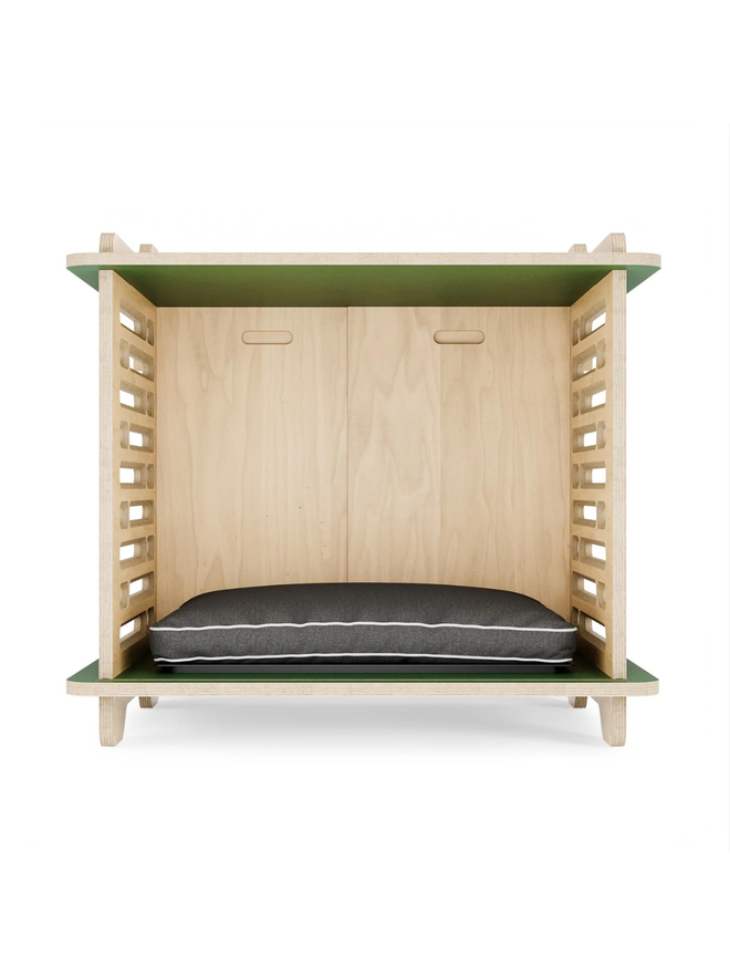 wooden dog crate interior with green top and cushion