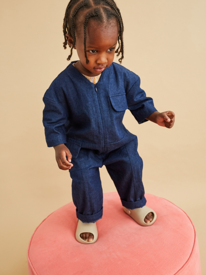 toddler wearing oversized denim linen boilersuit  looking very cool. Overalls by small brand studio koter made in the UK and stocked at www.studio-koter.com as well as triangle store, cissy wears and ando stores.