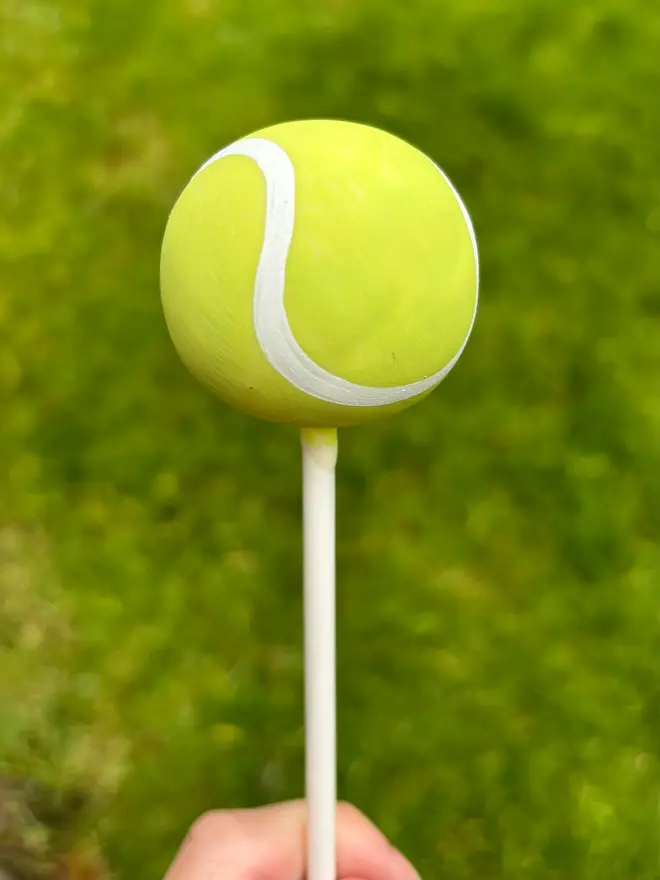 tennis ball cake pop. a tennis ball shaped cake pop on a stick.