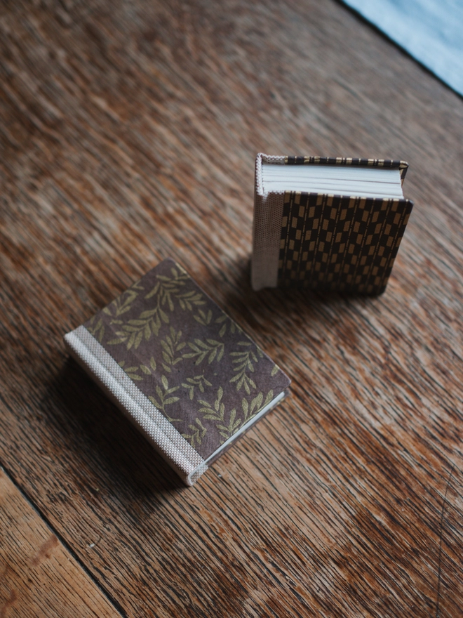 Two miniature hardback journals, with assorted brown and gold printed covers