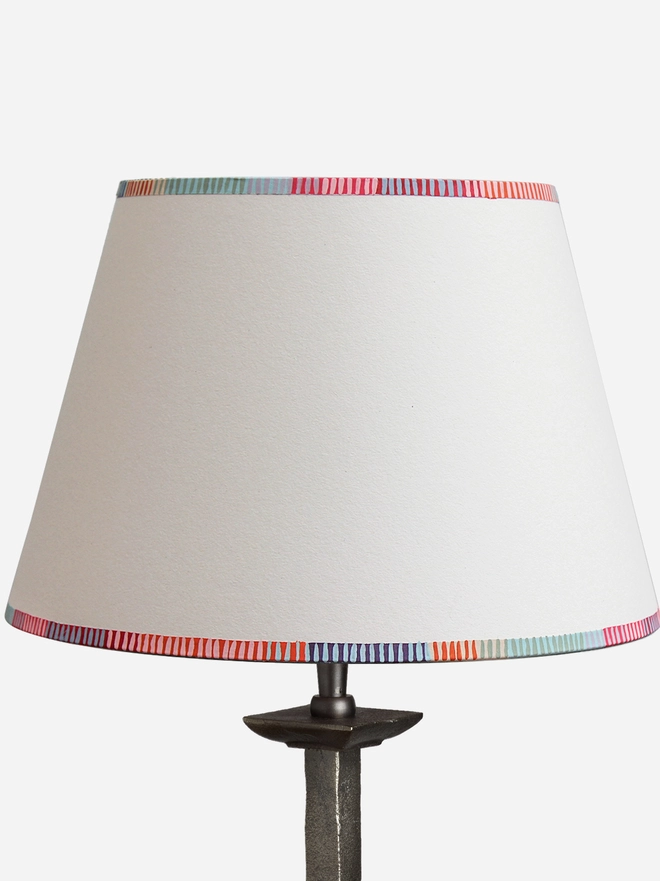 Empire lampshade with a colourful striped edge design, perfect as a bold stripe lampshade for table lamps. This modern empire light shade features vibrant red, pink, blue, and orange striped detailing along the top and bottom rims, adding a playful touch to striped lighting in any interior. A pretty lampshade ideal for UK homes looking for unique striped lampshades.