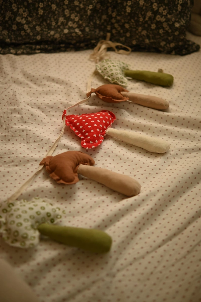 Mushroom Garland Decoration, a mushroom garland sitting on a child's bed. 