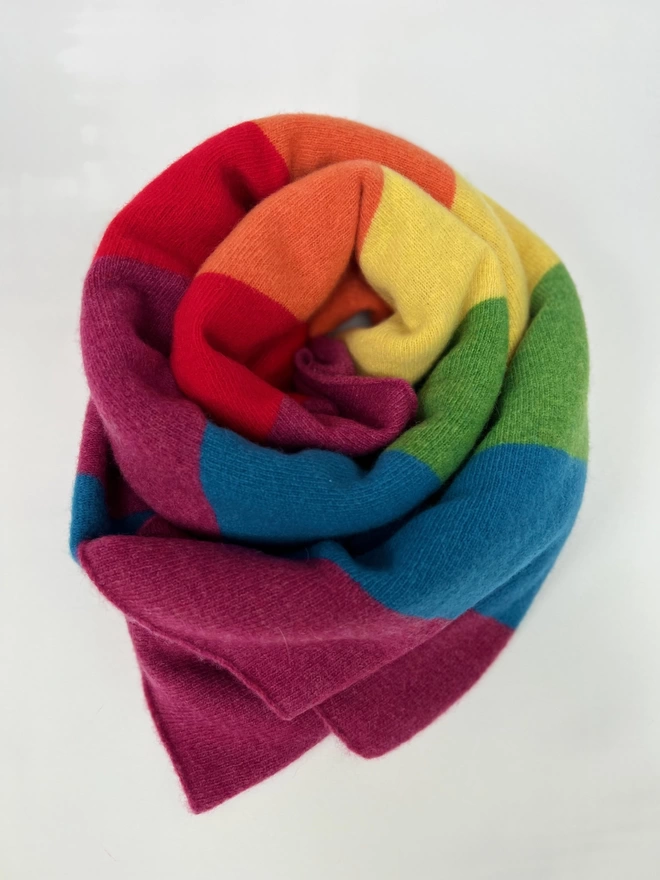 Knitted rainbow blanket shown rolled 