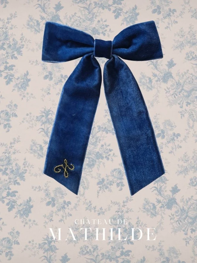 hand embroidered initials hair bow. a blue hair bow with a gold H initial.